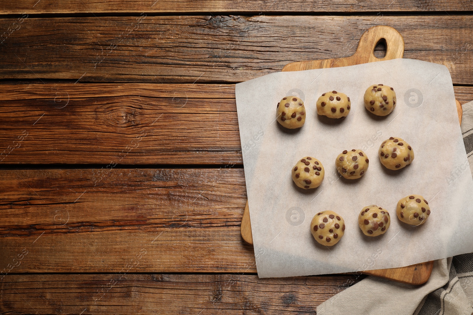 Photo of Uncooked chocolate chip cookies on wooden table, top view. Space for text