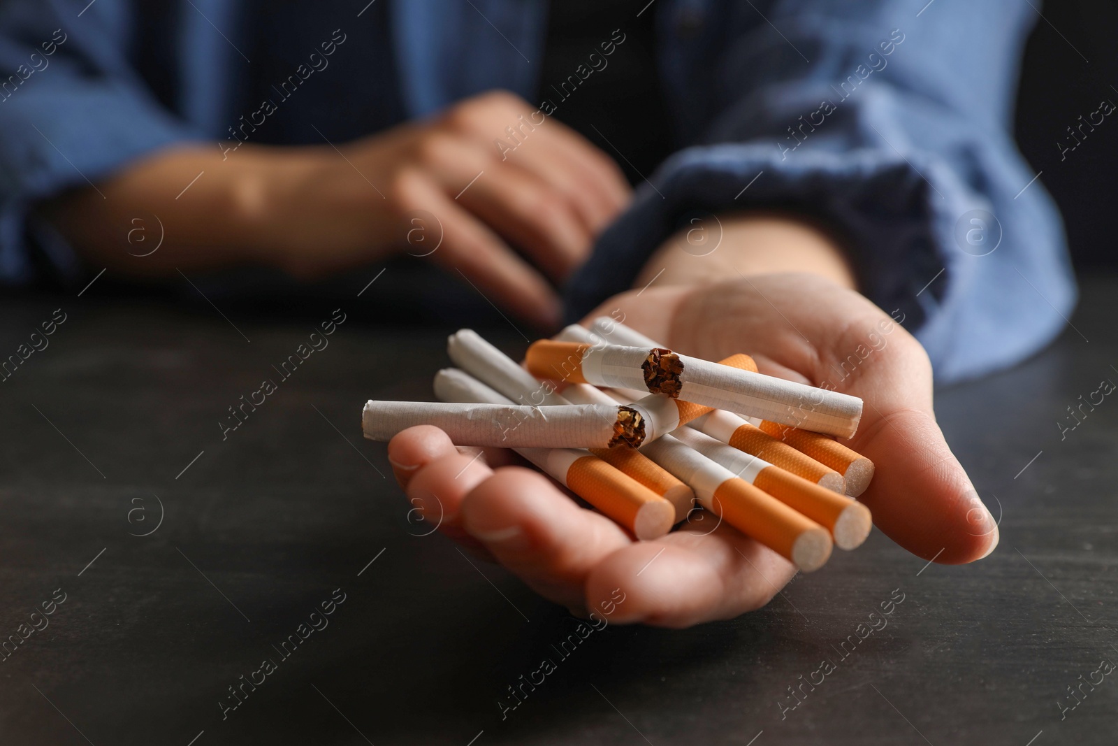 Photo of Stop smoking. Woman holding whole and broken cigarettes at black table, closeup