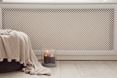 Photo of Glass vase with burning candles on floor indoors