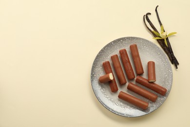 Photo of Glazed curd cheese bars, vanilla pods and flower on beige background, top view. Space for text