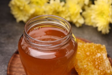 Photo of Sweet golden honey in jar on table, closeup