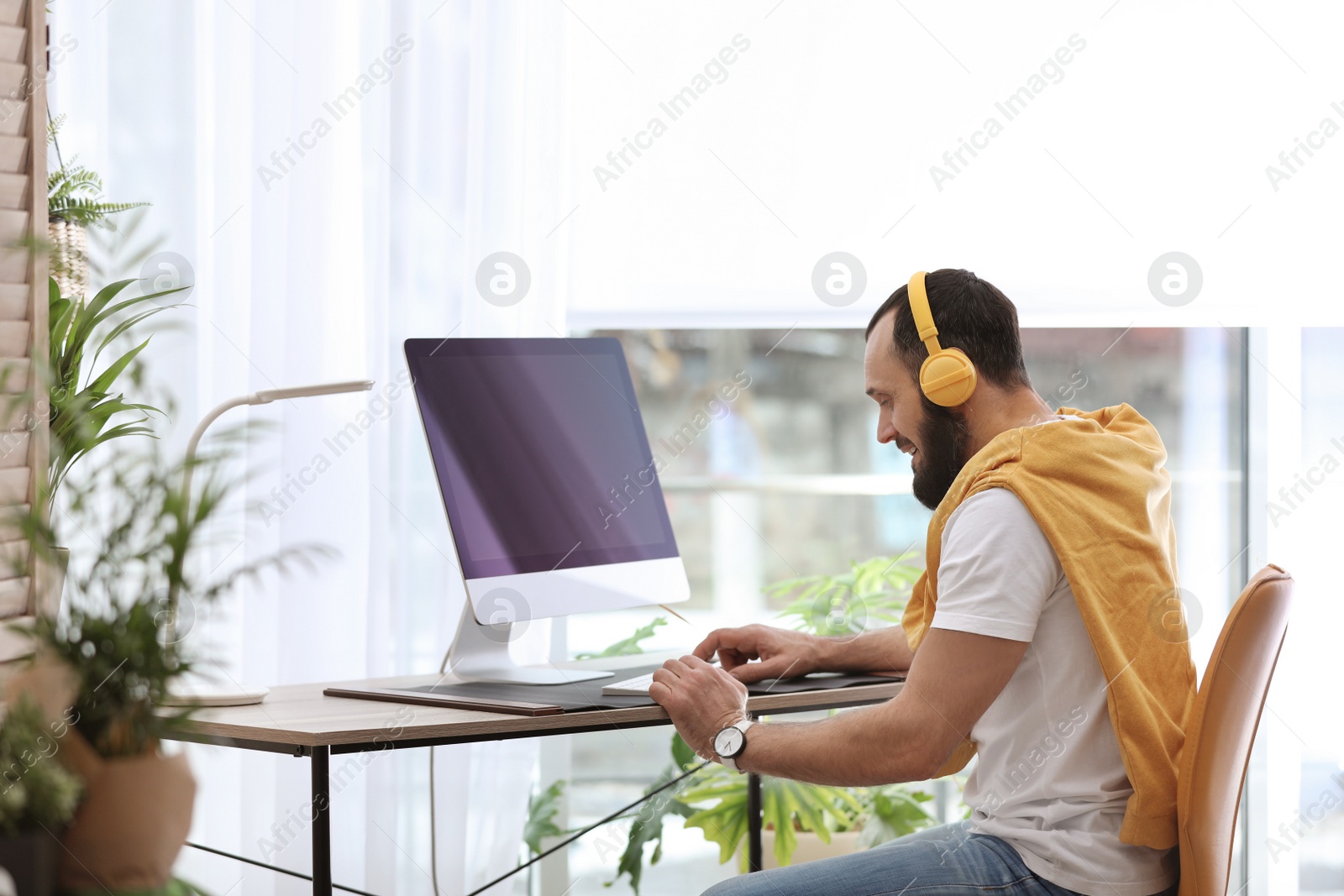 Photo of Mature man with headphones and computer in home office