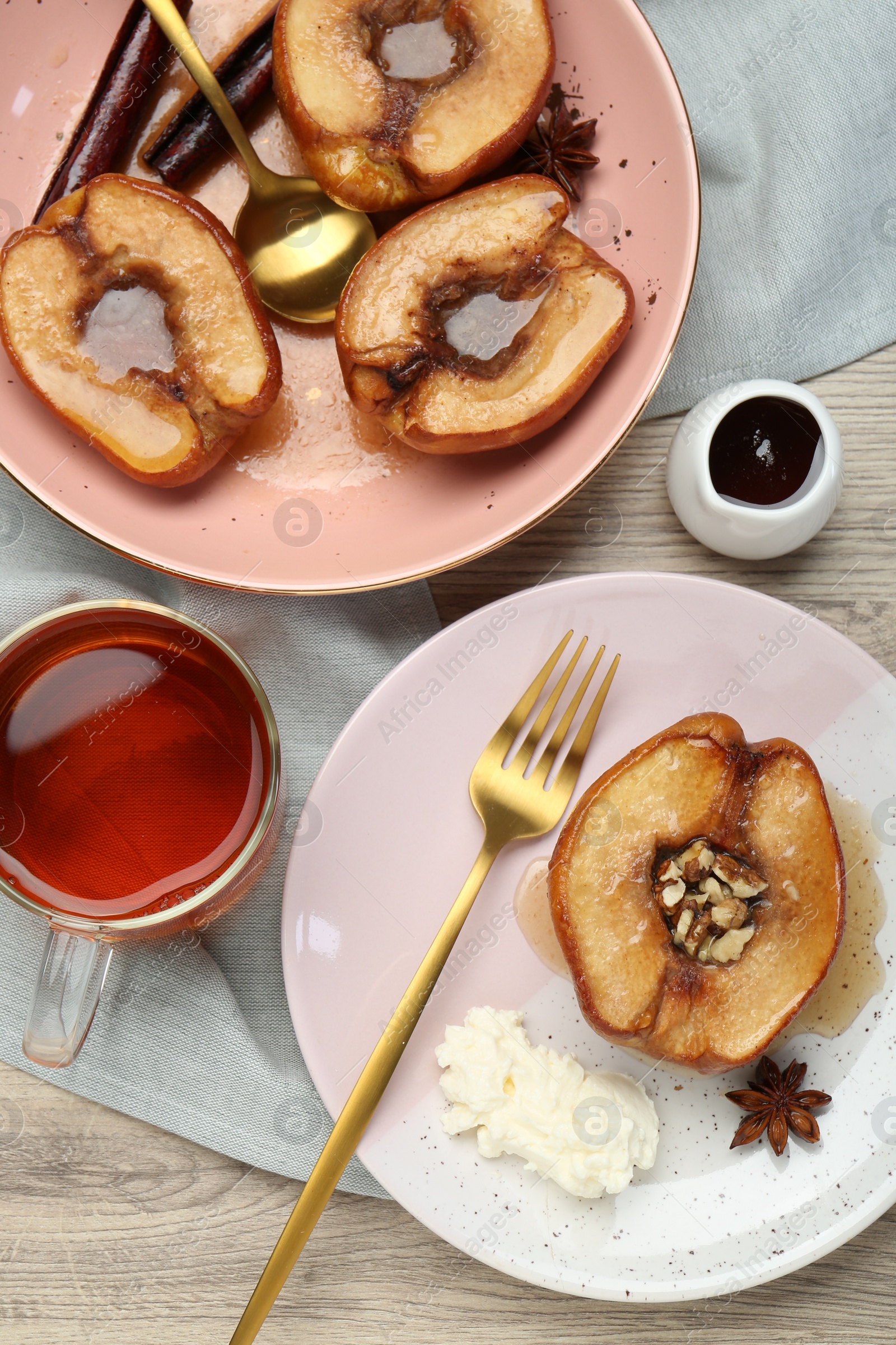 Photo of Delicious quinces baked with honey and walnuts on wooden table, flat lay
