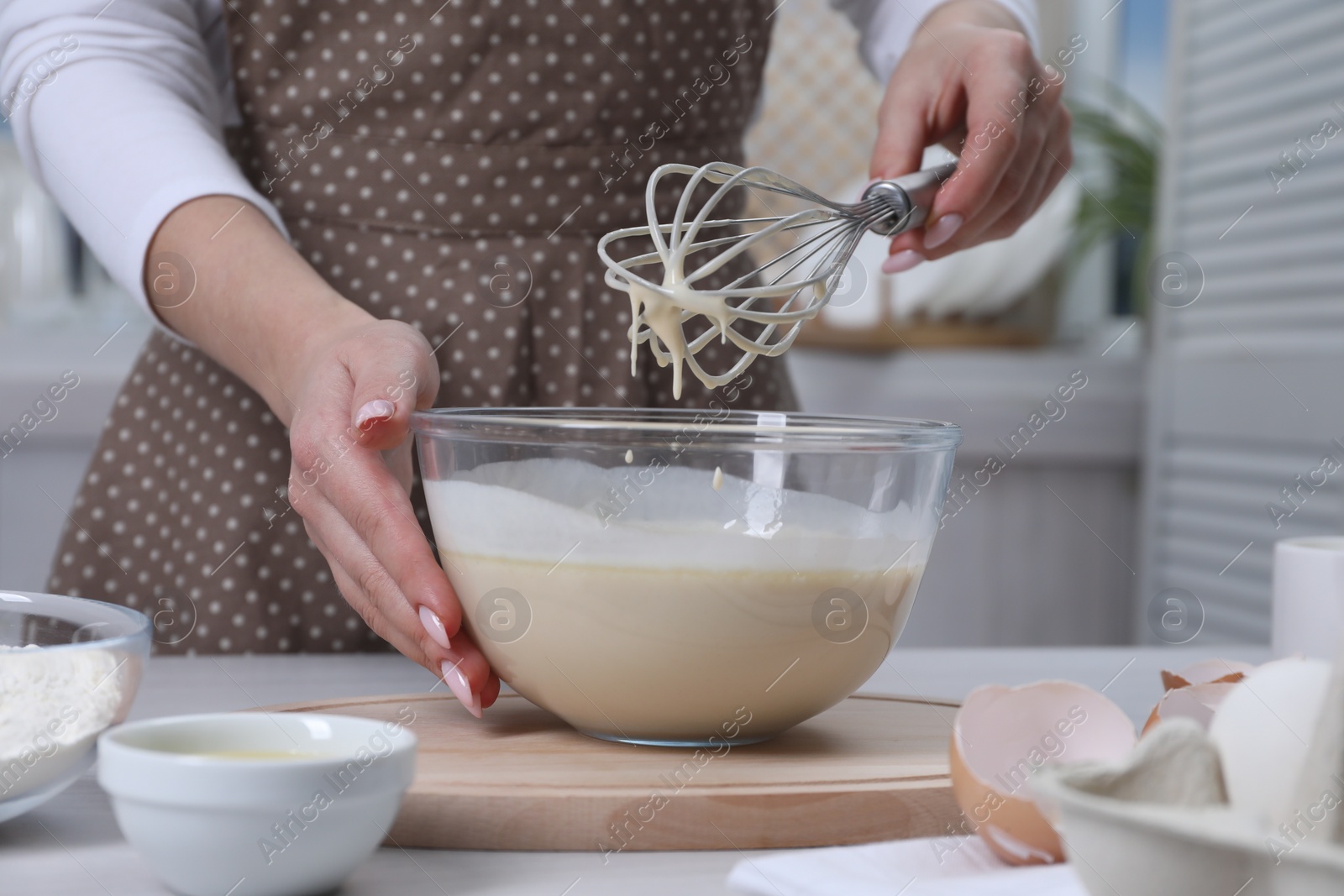 Photo of Woman making dough with whisk in bowl at table, closeup