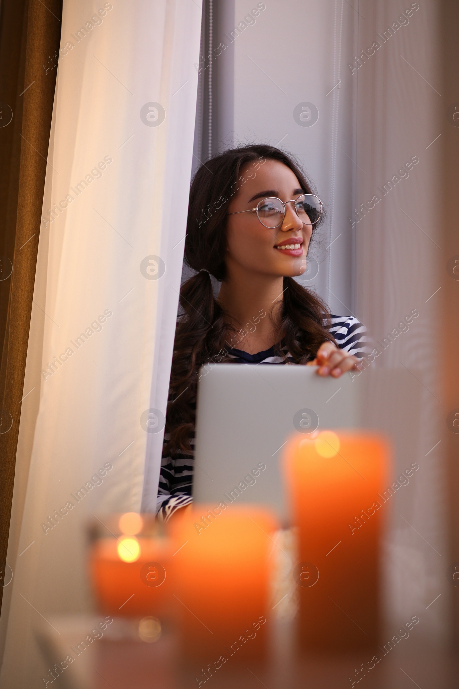 Photo of Young woman using laptop near window at home. Winter atmosphere