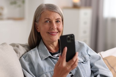 Photo of Senior woman using mobile phone at home