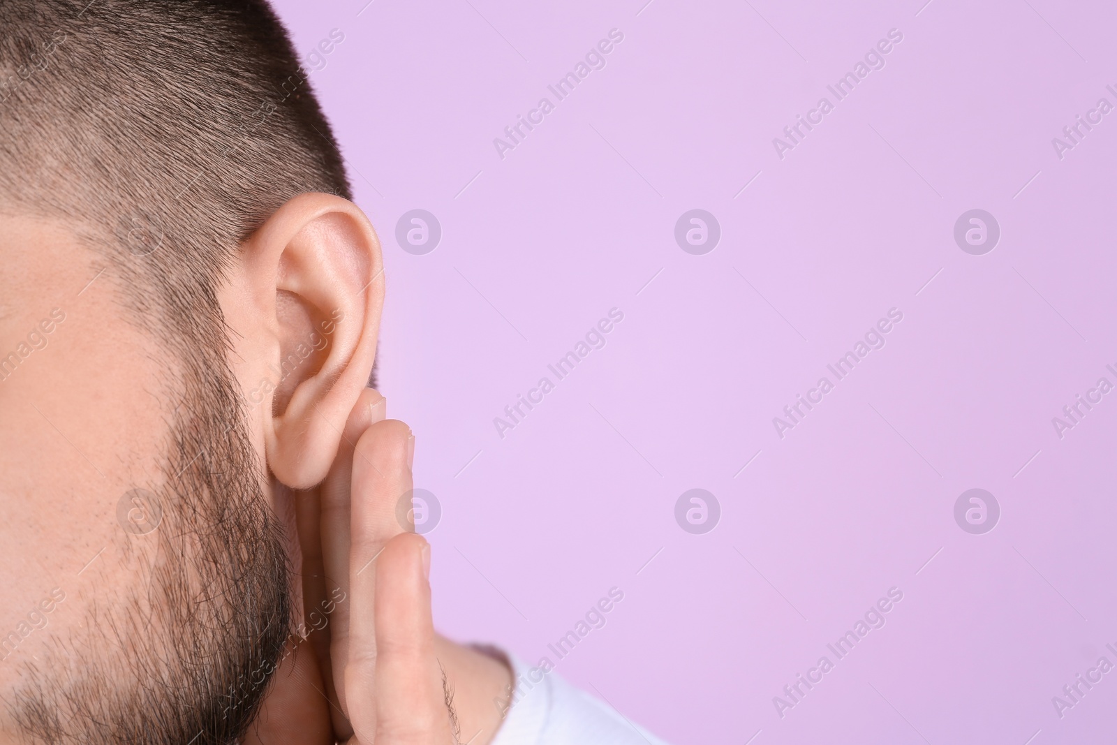 Photo of Young man with hearing problem on color background, closeup. Space for text