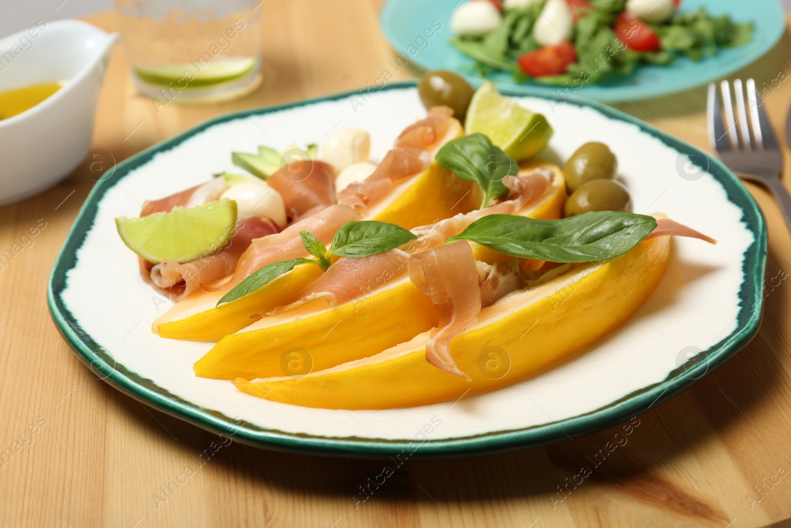 Photo of Plate with melon and prosciutto appetizer on wooden table