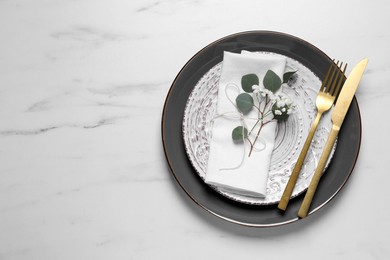 Stylish table setting with cutlery, flower and eucalyptus leaves, top view. Space for text