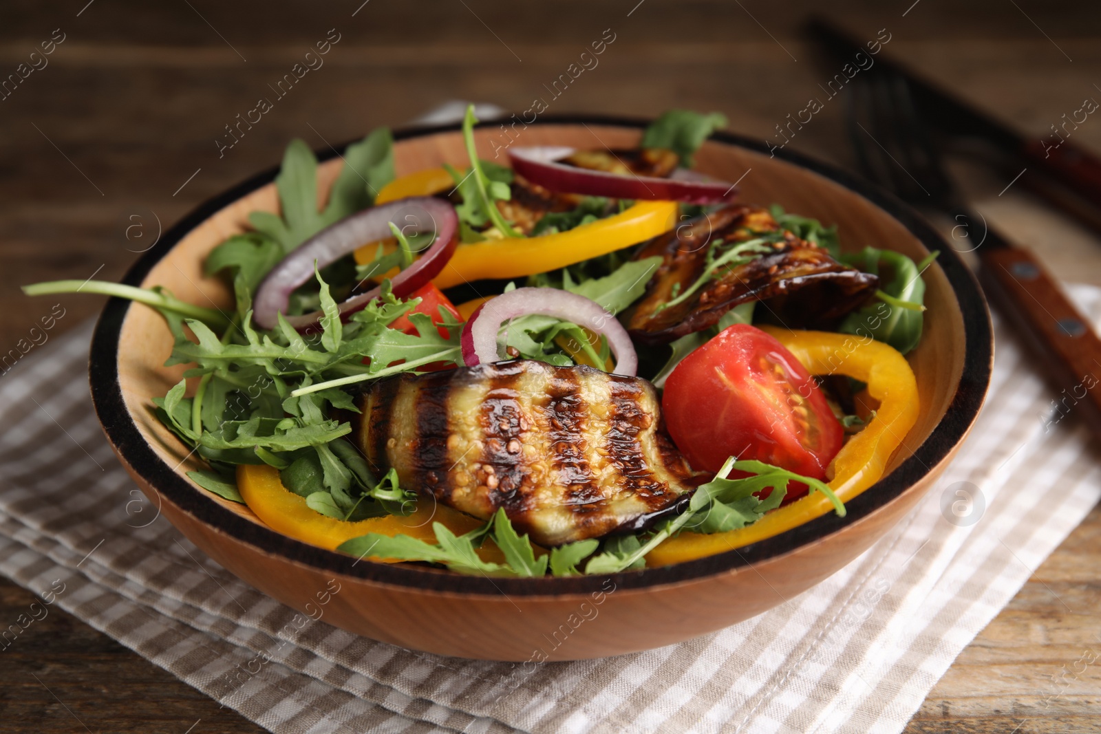 Photo of Delicious salad with roasted eggplant and arugula served on table