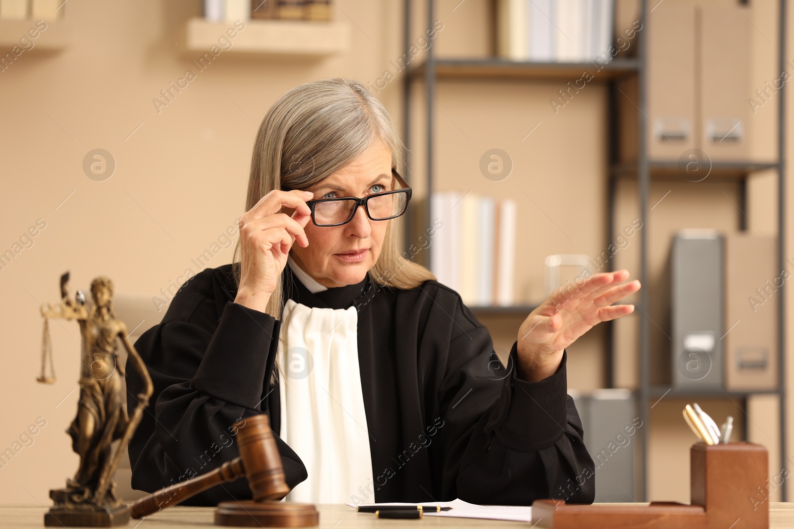 Photo of Judge in court dress working at table indoors