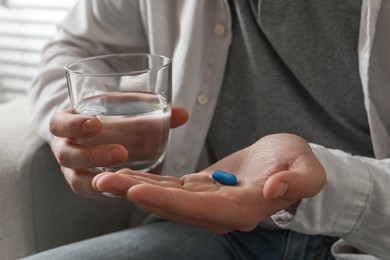 Photo of Man with glass of water and pill on blurred background, closeup