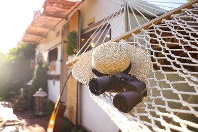 Photo of Comfortable hammock with hat and binocular near motorhome outdoors on sunny day