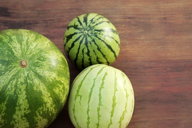 Photo of Different delicious ripe watermelons on wooden table, top view. Space for text