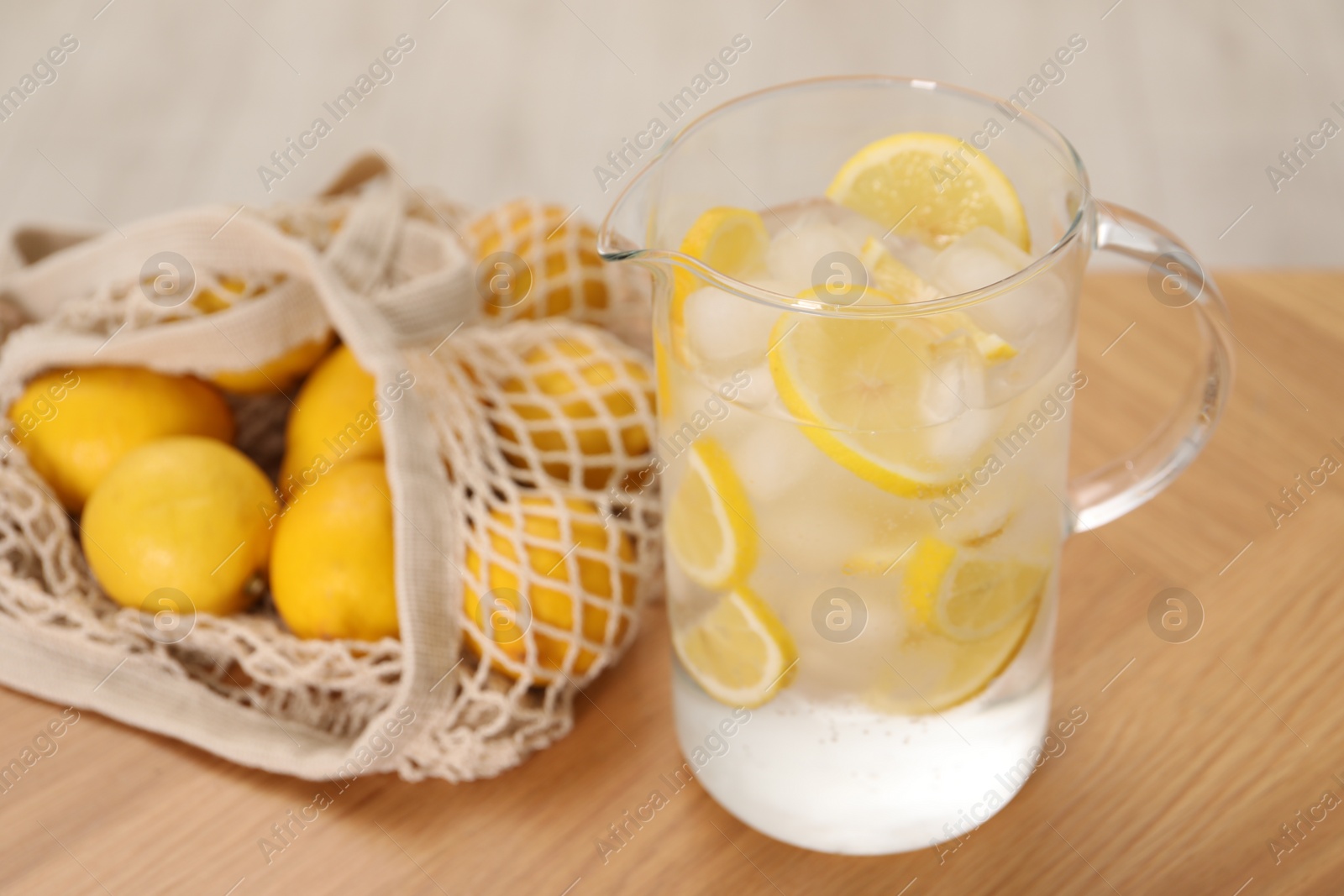 Photo of Freshly made lemonade in jug on wooden table indoors