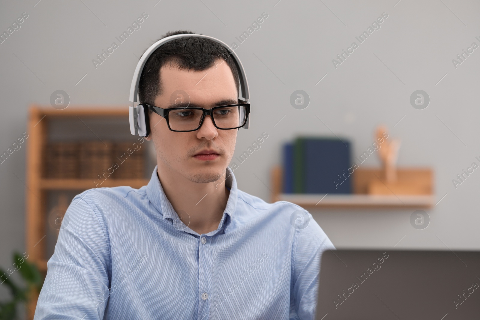 Photo of E-learning. Young man using laptop during online lesson indoors