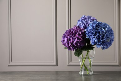 Photo of Bouquet with beautiful hortensia flowers on stone table near grey wall. Space for text