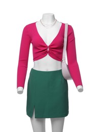 Female mannequin dressed in green skirt and pink top with accessories isolated on white. Stylish outfit