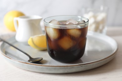 Photo of Refreshing iced coffee in glass and spoon on white wooden table, closeup