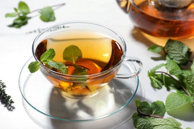 Cup of aromatic herbal tea with mint and thyme on white table
