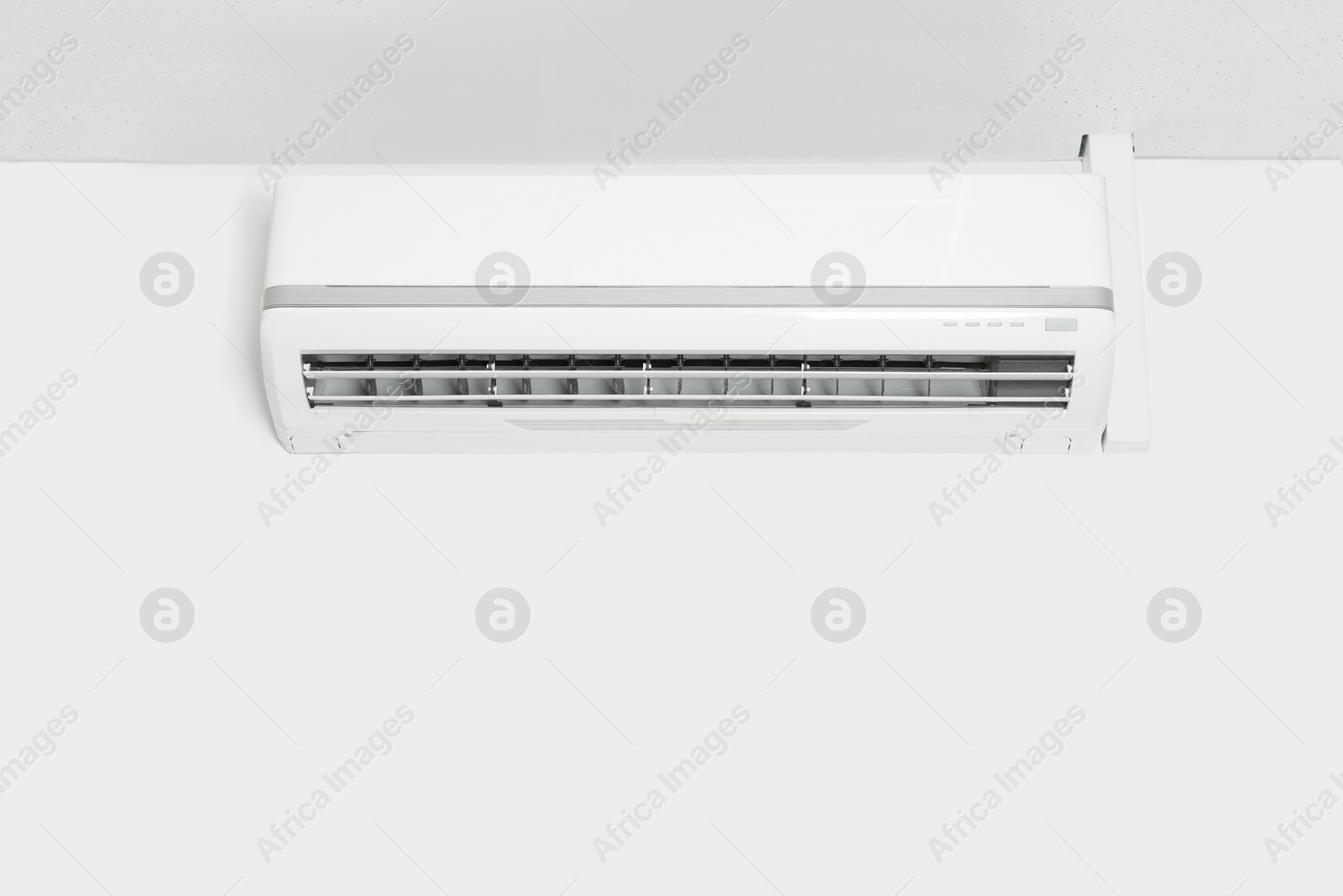 Photo of Modern air conditioner on white wall indoors. Space for text