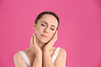 Photo of Portrait of beautiful mature woman on pink background. Space for text