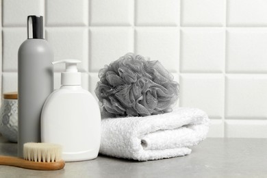 Photo of Different bath accessories and personal care products on gray table near white tiled wall