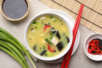 Bowl of delicious miso soup with tofu served on light grey table, flat lay