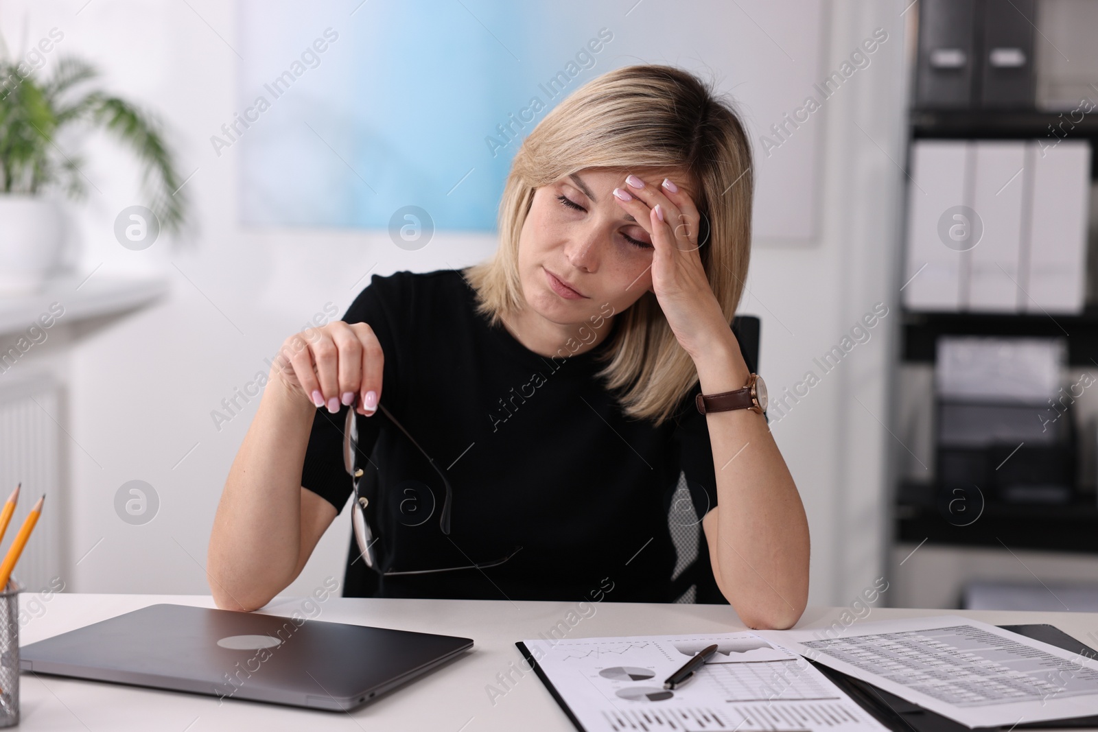 Photo of Overwhelmed woman with glasses sitting at table in office