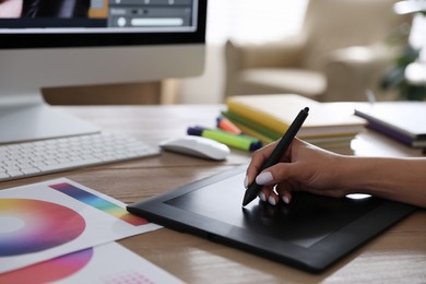 Photo of Professional retoucher working on graphic tablet at table, closeup