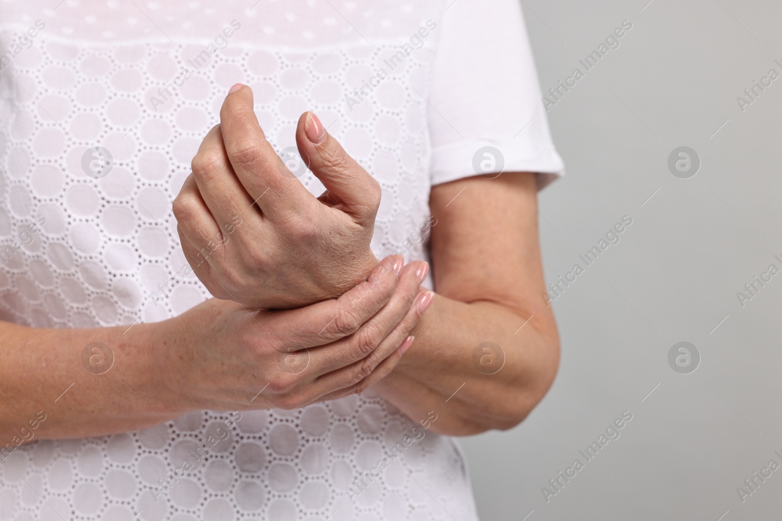 Photo of Arthritis symptoms. Woman suffering from pain in wrist on gray background, closeup