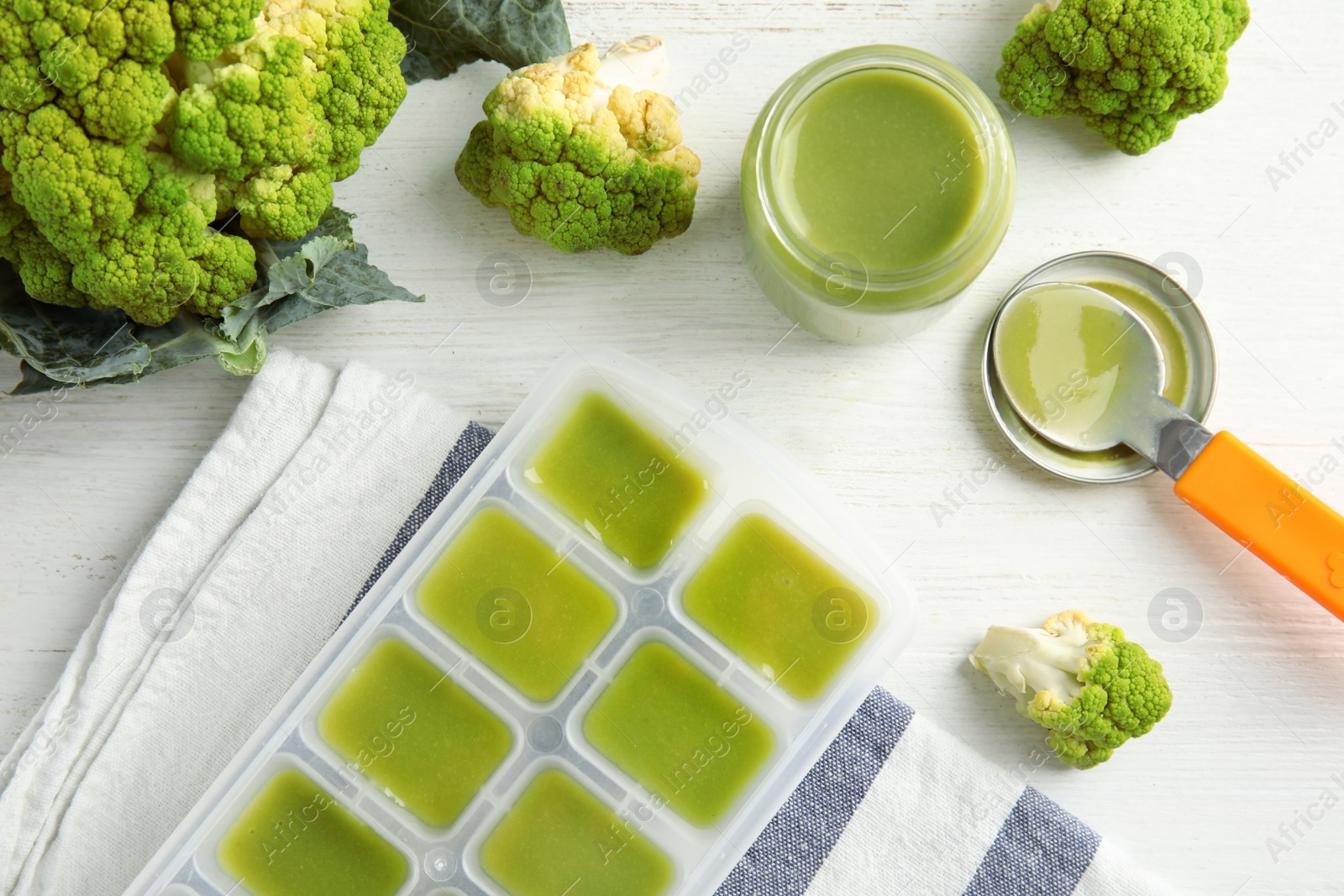 Photo of Flat lay composition with ice cube tray of baby food on wooden background