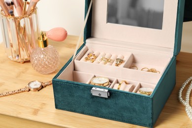 Photo of Jewelry box with many different accessories, perfume and makeup brushes on wooden table