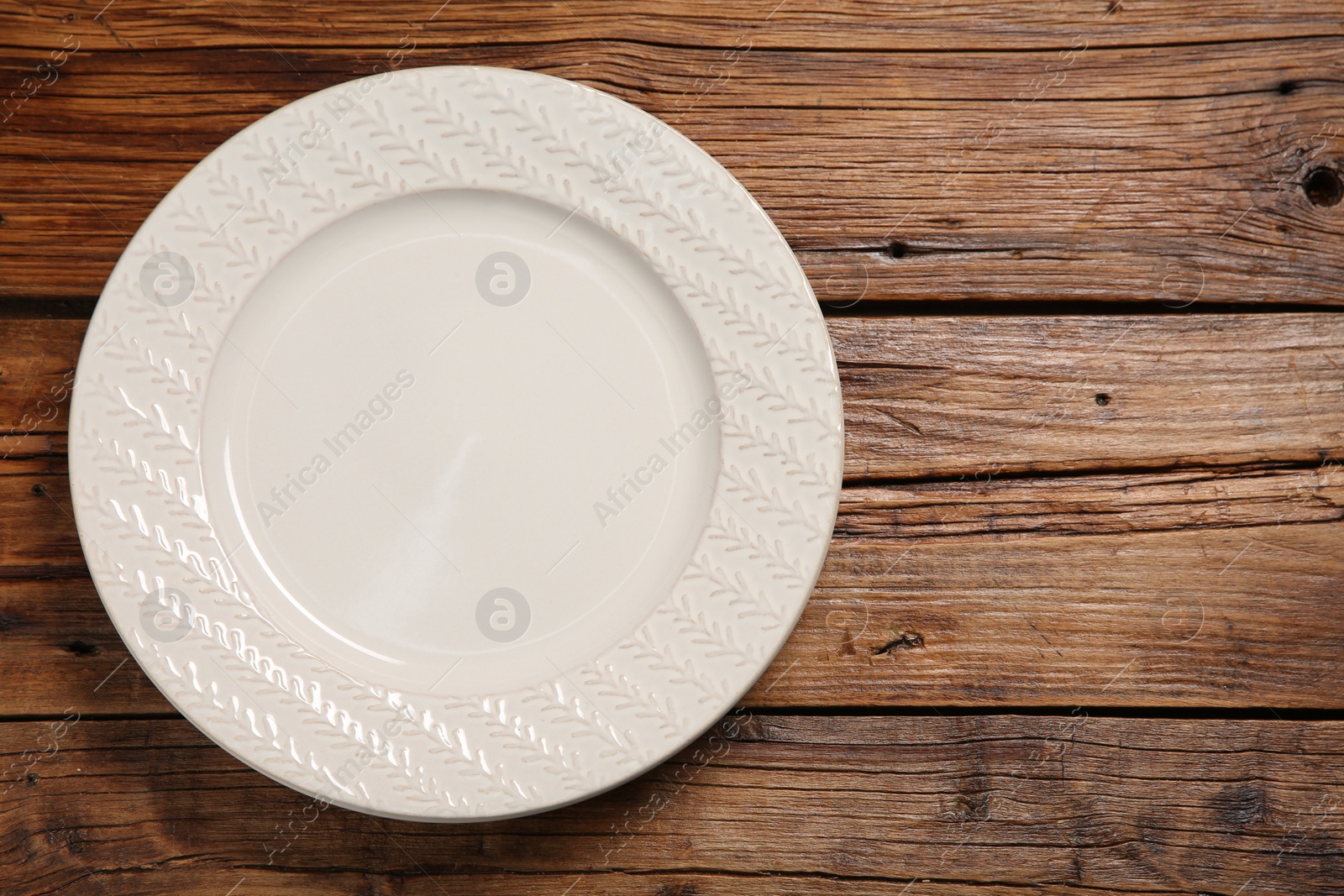 Photo of One ceramic plate on wooden table, top view. Space for text