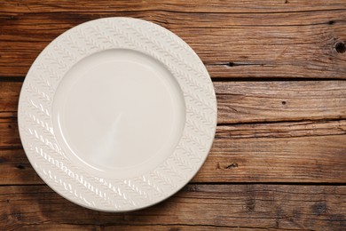 Photo of One ceramic plate on wooden table, top view. Space for text