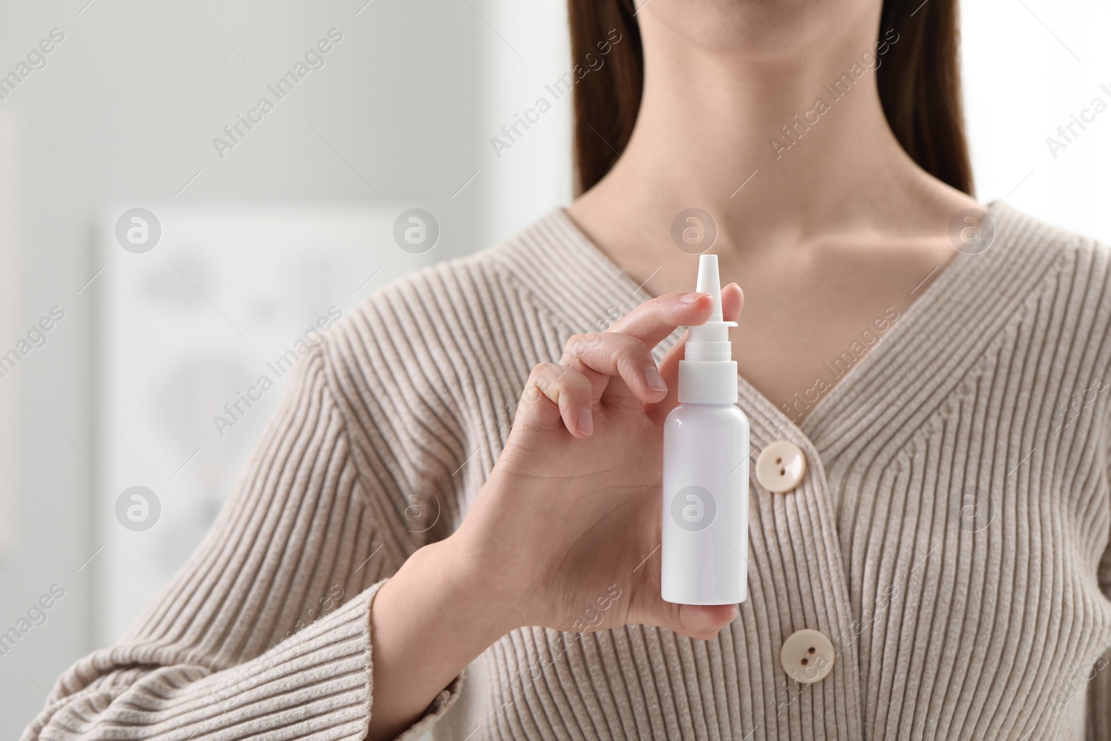 Photo of Woman holding nasal spray indoors, closeup view