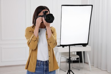 Photo of Professional photographer taking picture in modern photo studio, space for text