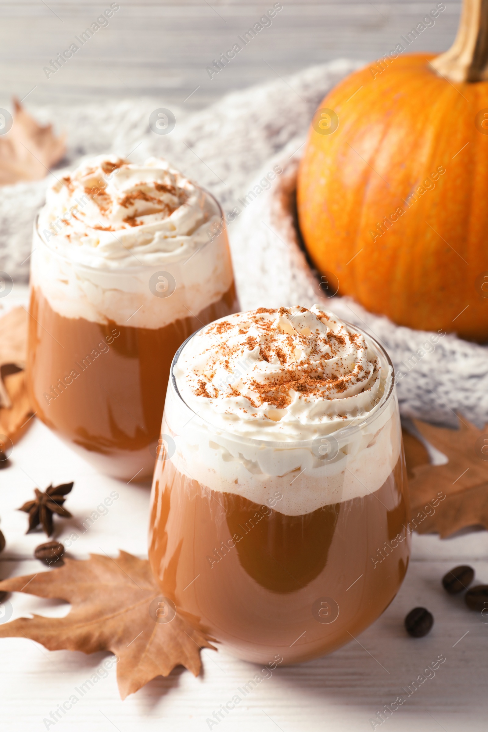 Photo of Glasses with tasty pumpkin spice latte on wooden table