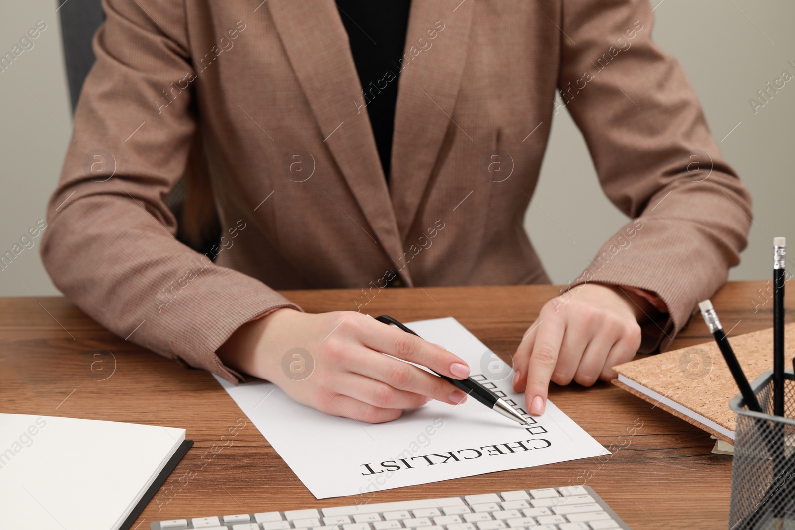 Photo of Woman filling Checklist at wooden table, closeup