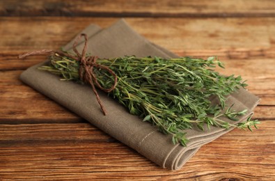 Photo of Bunch of aromatic thyme and napkin on wooden table