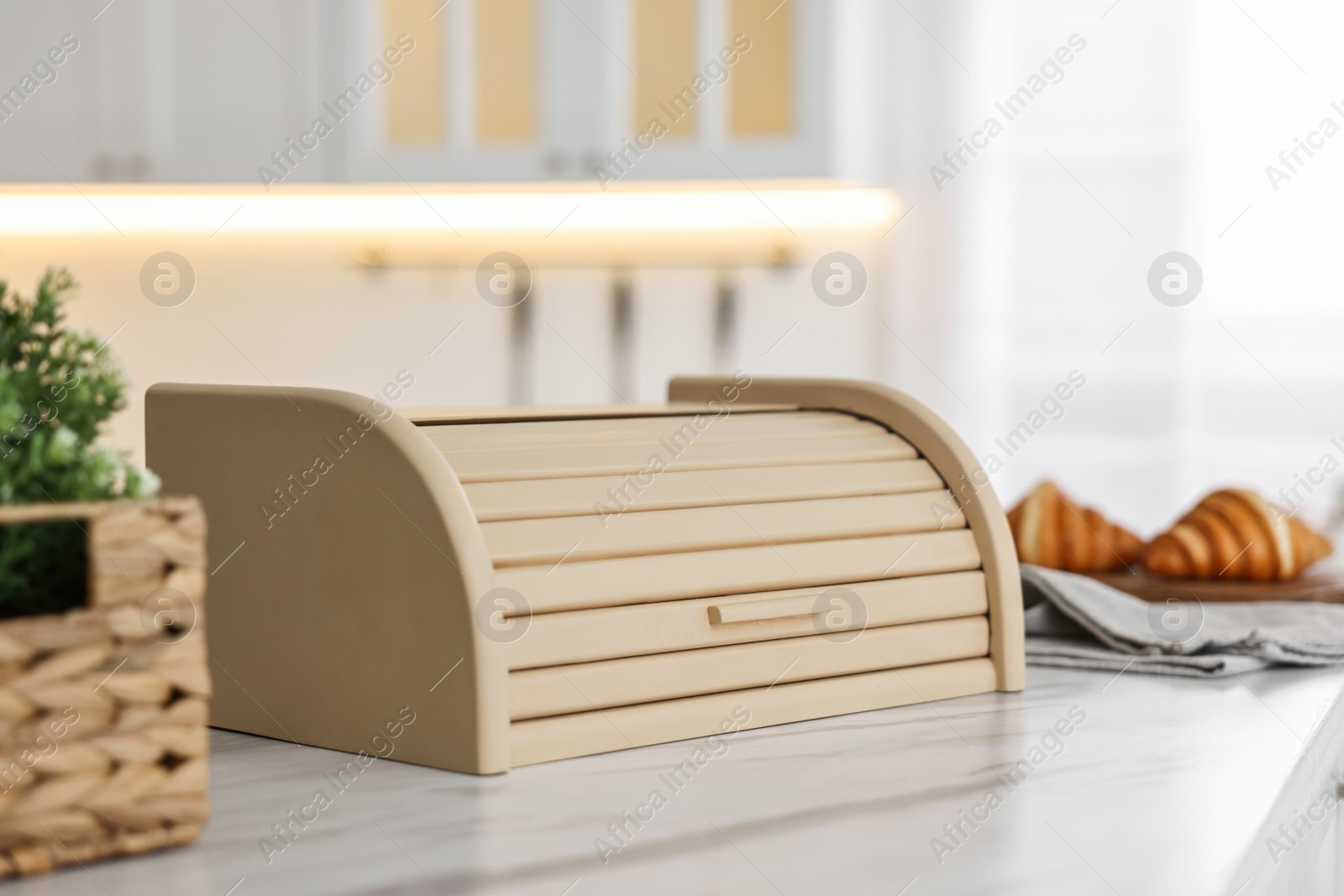 Photo of Wooden bread box on white marble table in kitchen