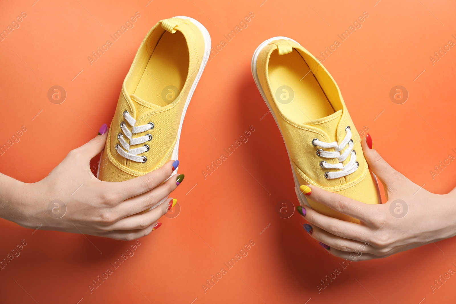 Photo of Young woman holding new sneakers on color background, closeup