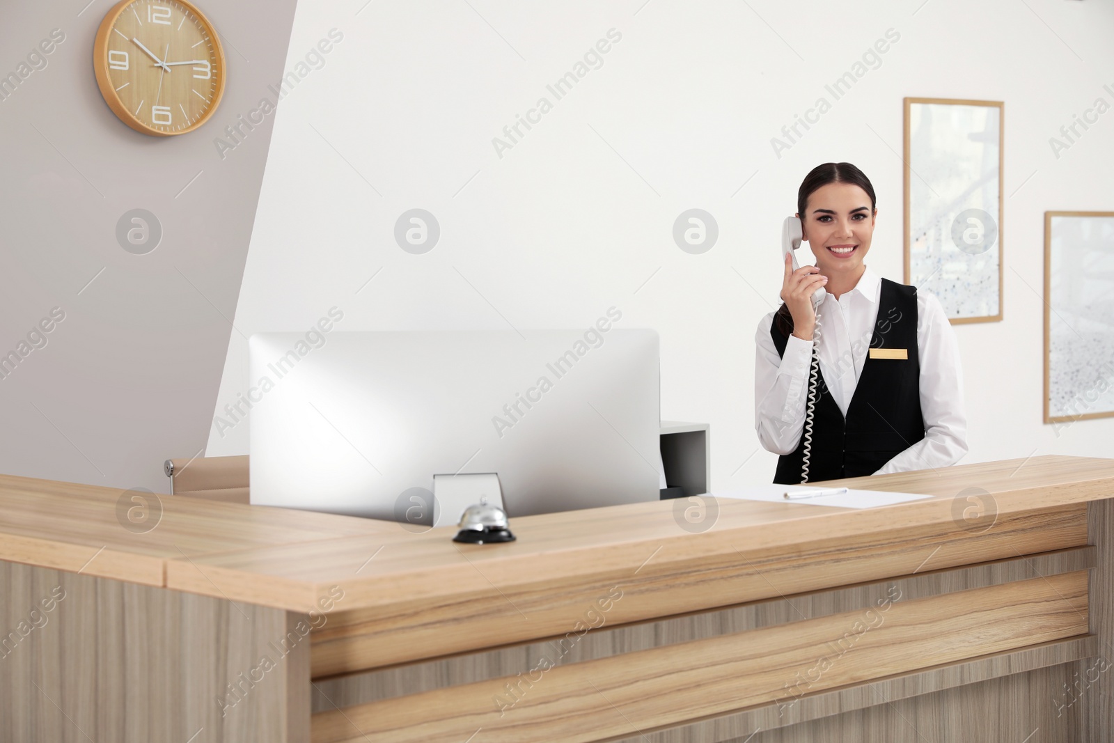 Photo of Receptionist talking on telephone near desk in modern hotel