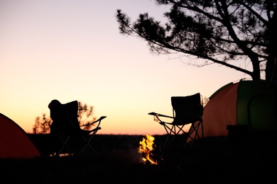 Photo of Camping tents and chairs in wilderness at sunset