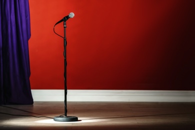 Photo of Microphone on stage against color wall. Space for text