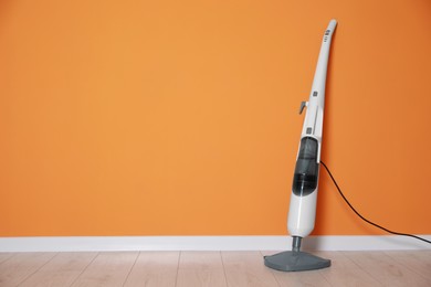 Photo of One modern steam mop on floor near orange wall, space for text
