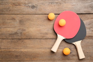 Photo of Ping pong rackets and balls on wooden table, flat lay. Space for text