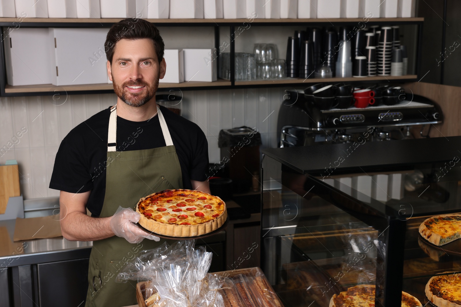 Photo of Seller with freshly baked quiche at cashier desk in bakery shop