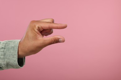 Photo of Man holding something in hand on pink background, closeup. Space for text