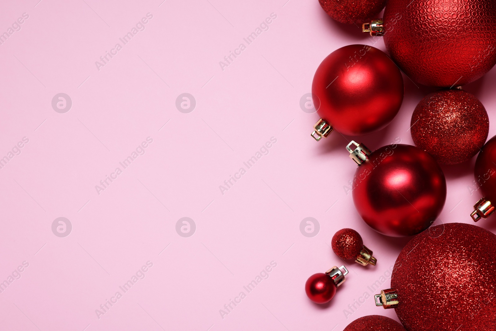 Photo of Shiny red Christmas balls on pink background, flat lay. Space for text